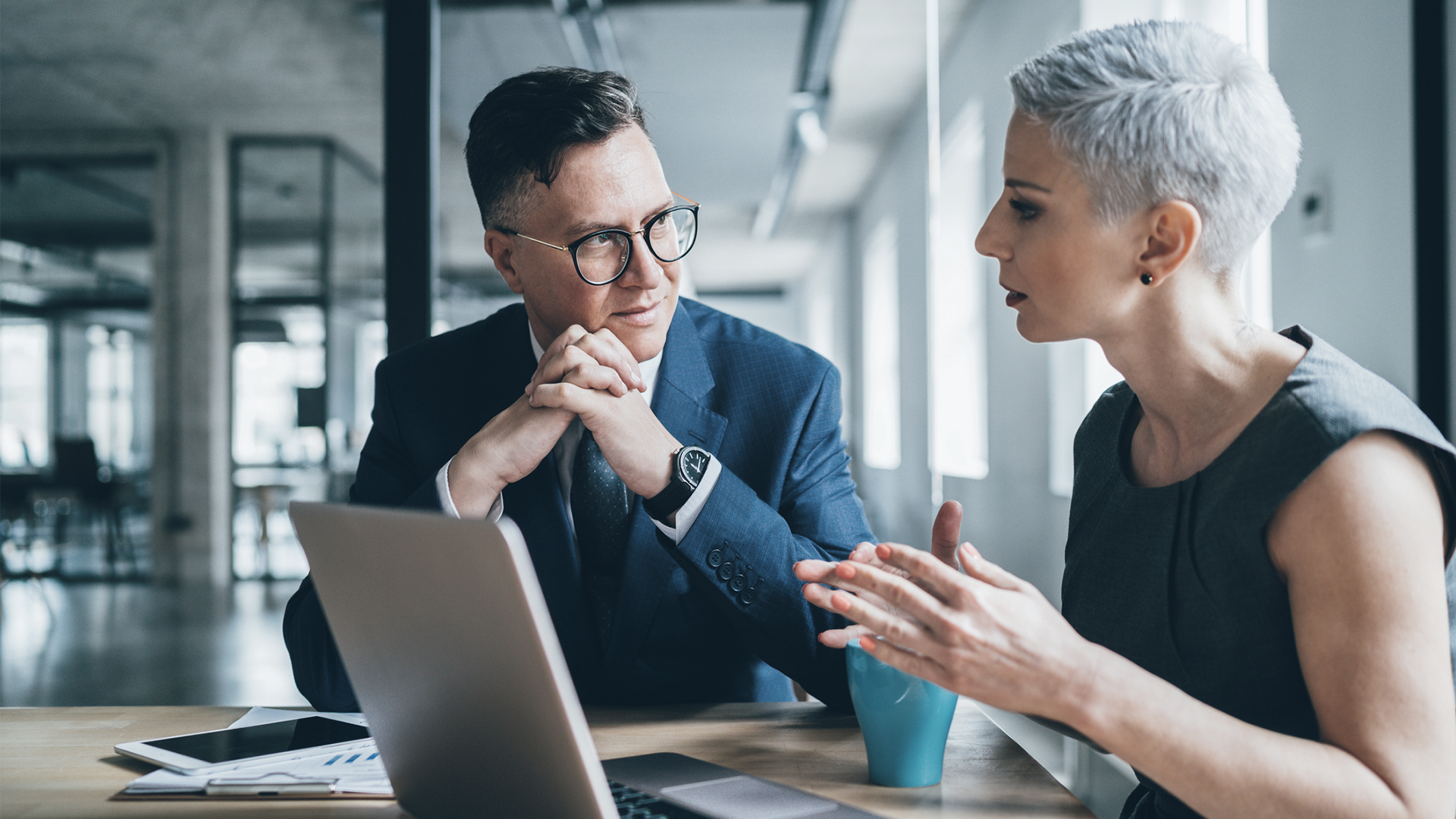 Colleagues discussing work while sitting at a laptop